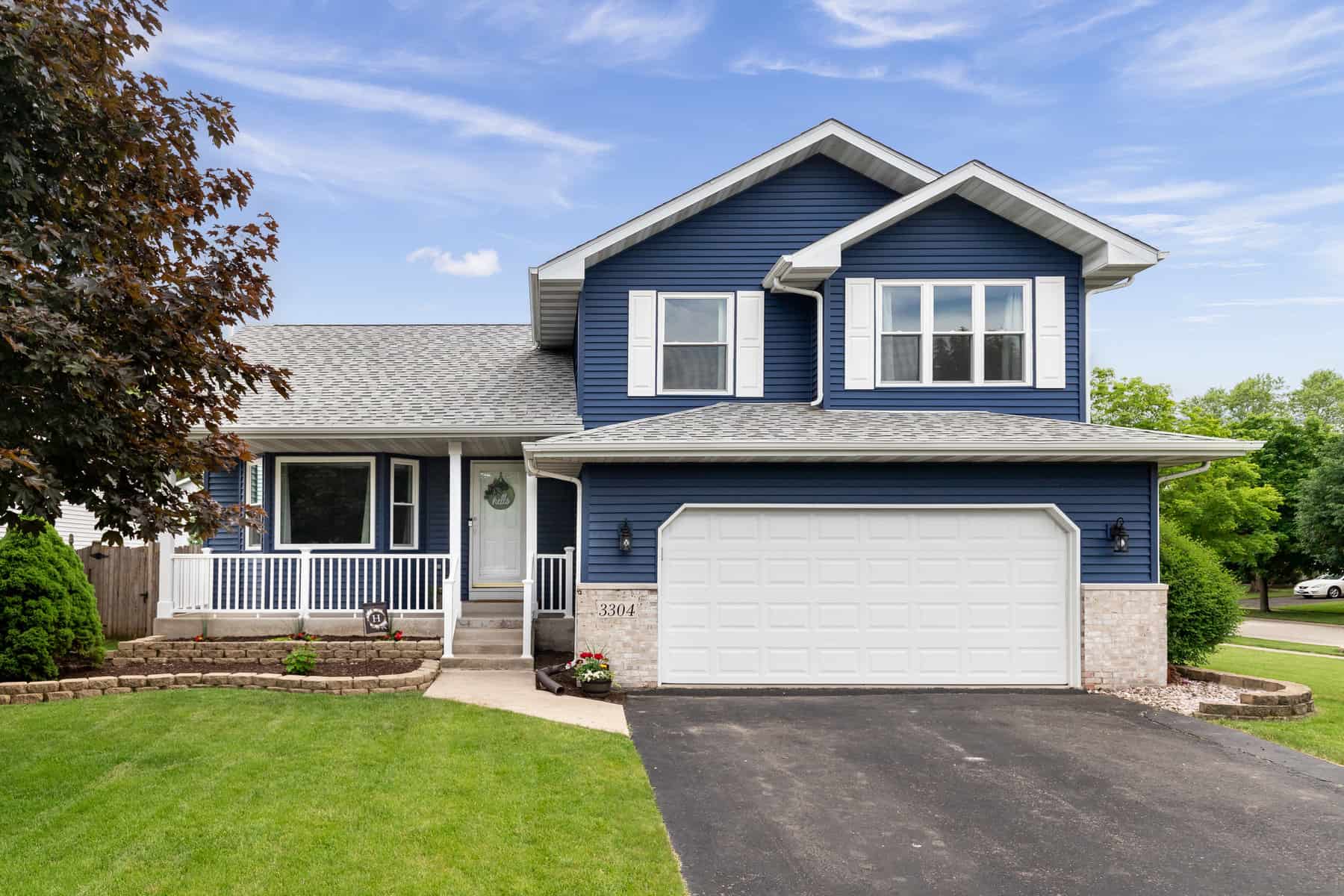 Exterior of a suburban home with blue siding, a white front porch, and white shutters.