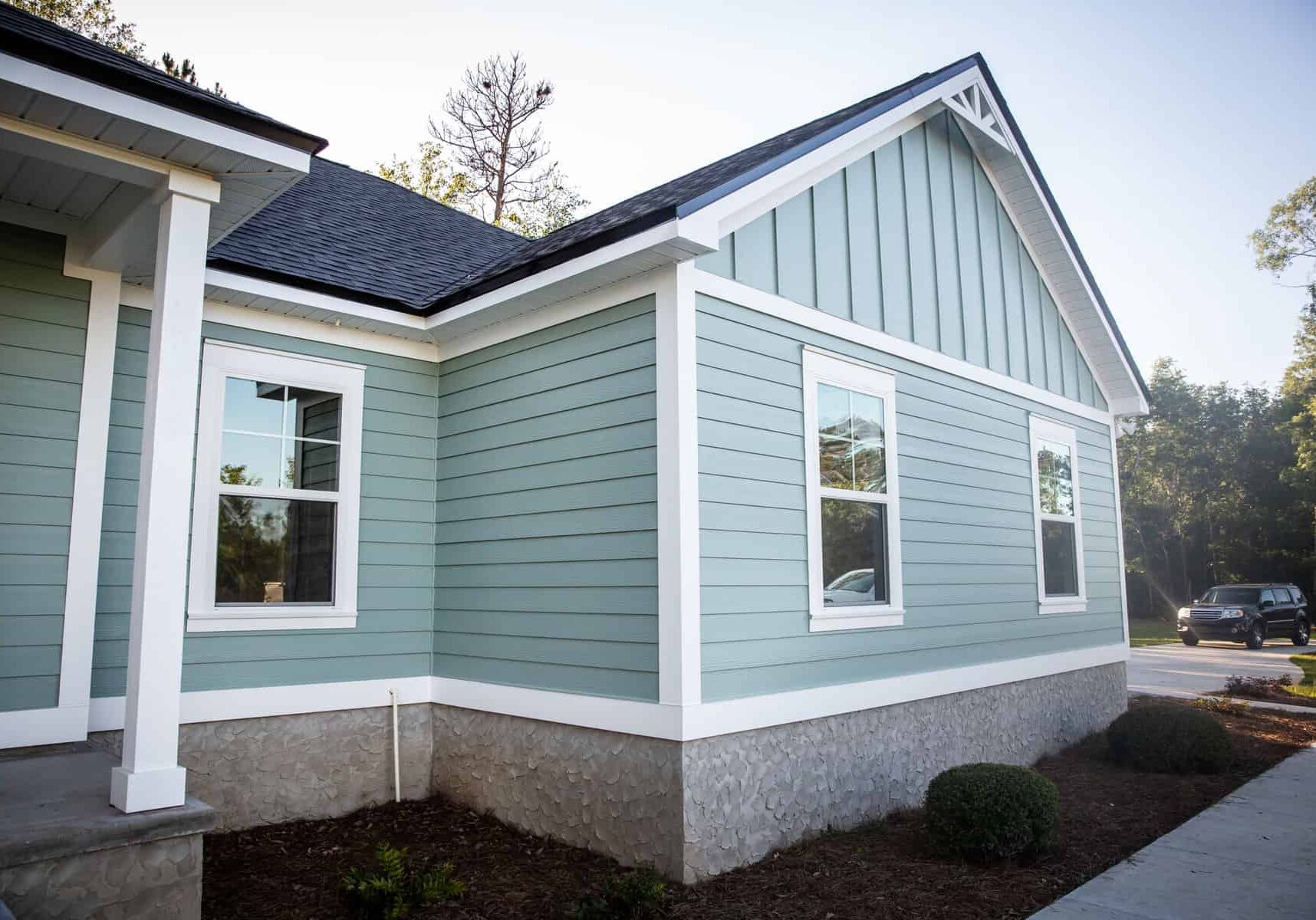Front view of a brand new construction house with blue siding, a  ranch style home with a yard