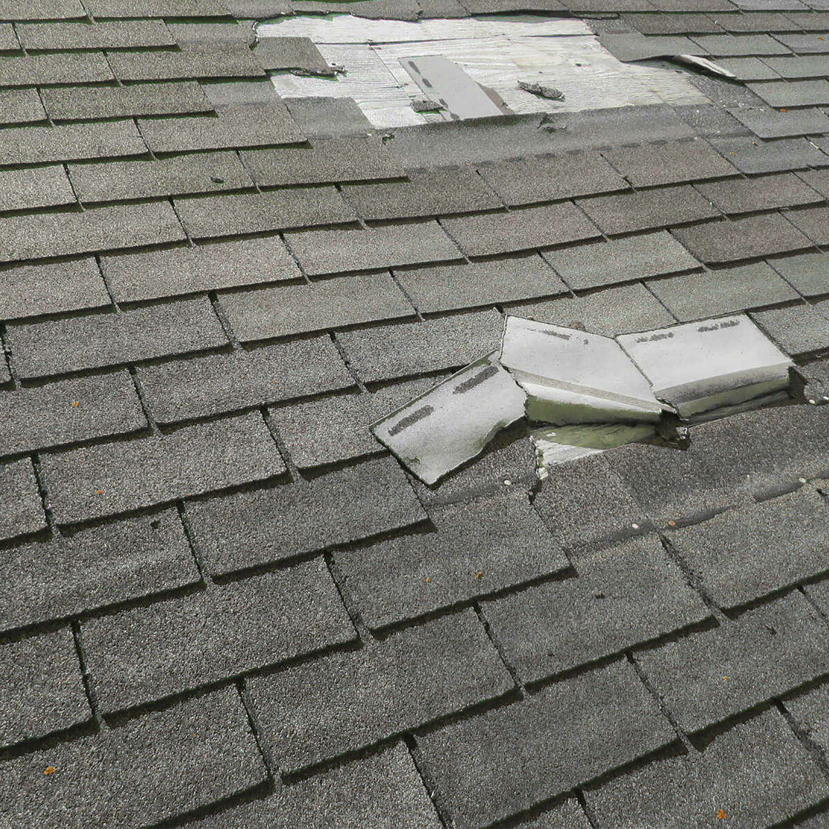 Close up of a roof with blown off shingles in Indiana. Indy Exterior Services is the best storm damage roofing company in Shelbyville, IN.